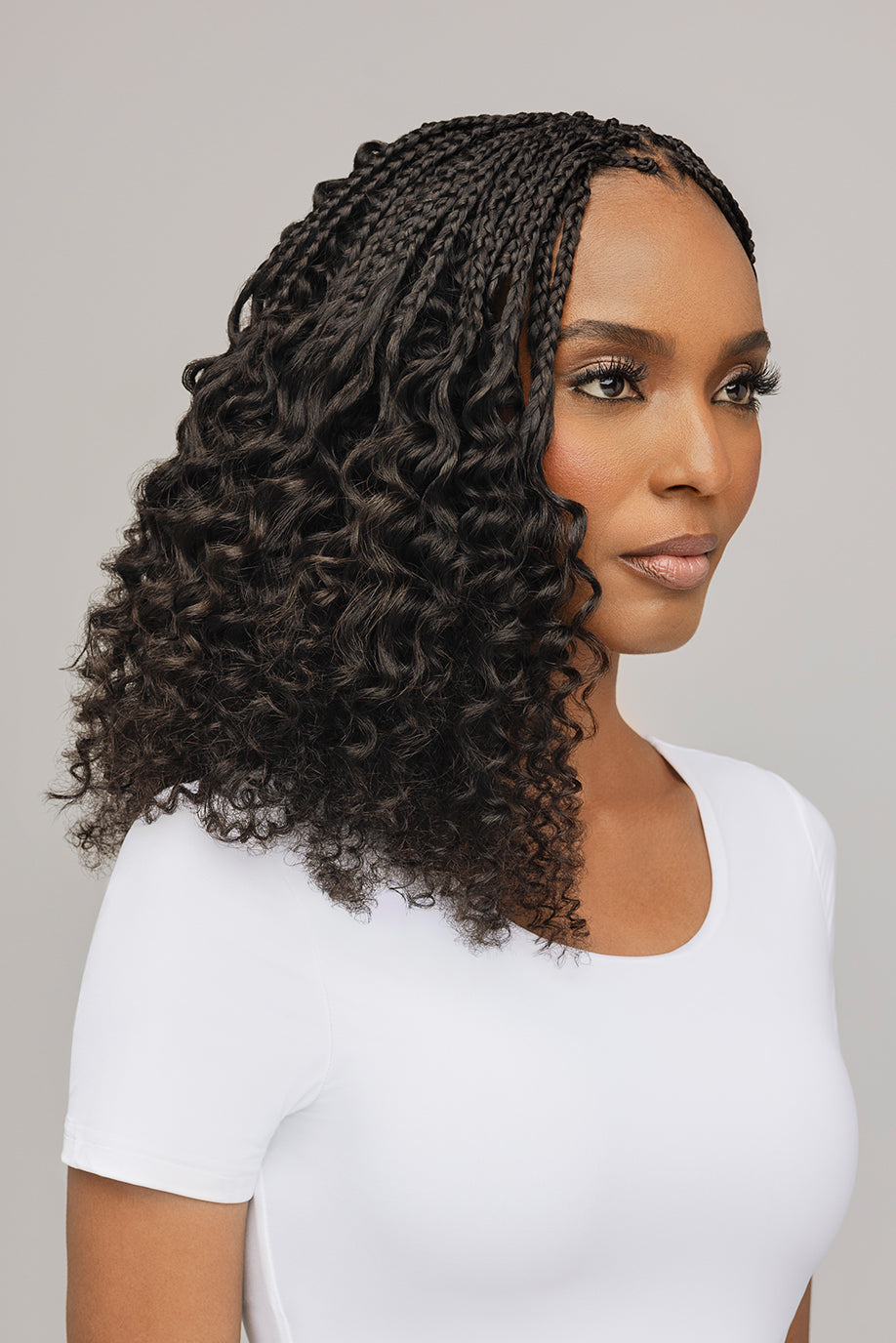 A woman with braided and curly hair wearing a white shirt.