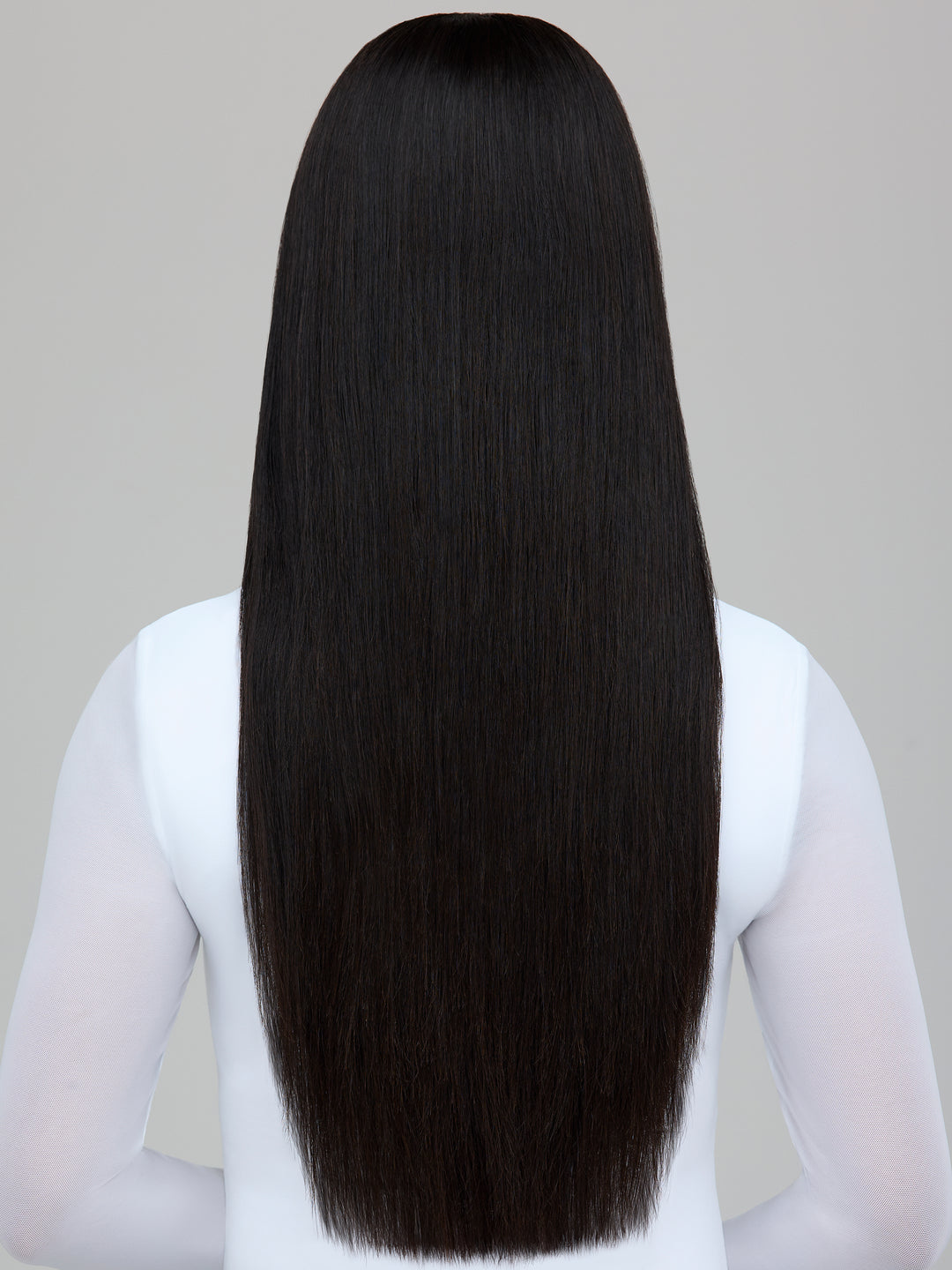 A person shown from the back wearing a long, straight black wig or hair extension against a plain light gray background.